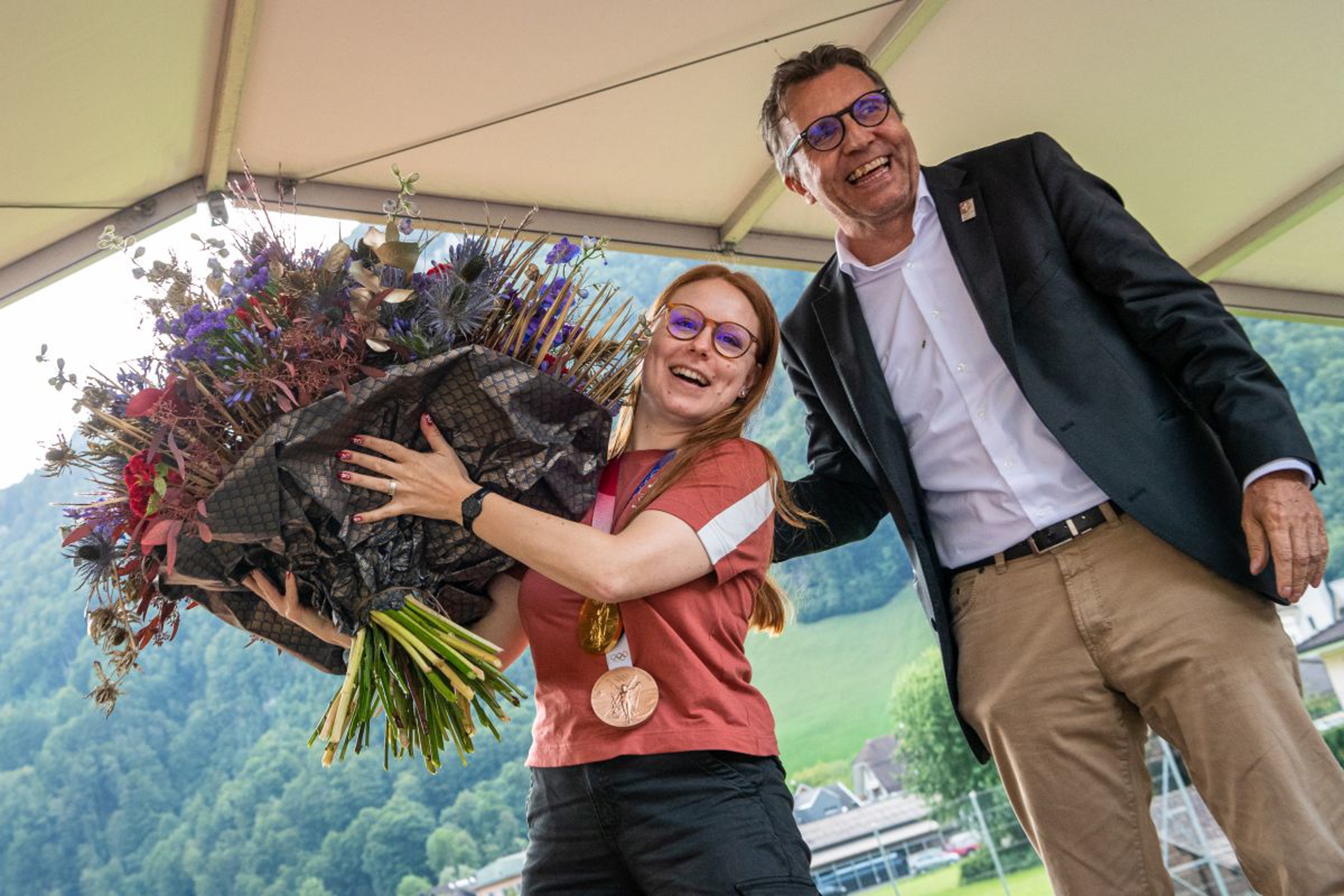 Daniel Bareiss, membro del comitato di Swiss Olympic, consegna alla campionessa olimpica un grande mazzo di fiori. Foto: fotozug.ch